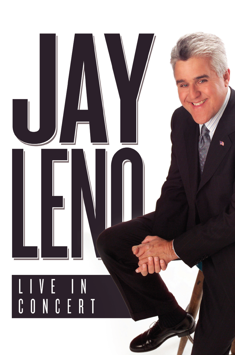 Comedian Jay Leno sits on a stool, hands clasped. He is smiling and wearing a black suit.